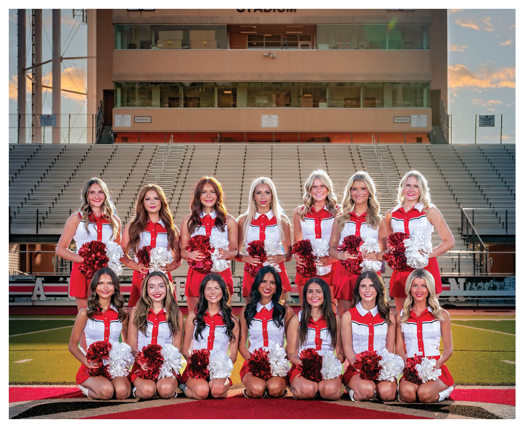 A group of cheerleaders pose for a photo in front of a stadium. AI generated content