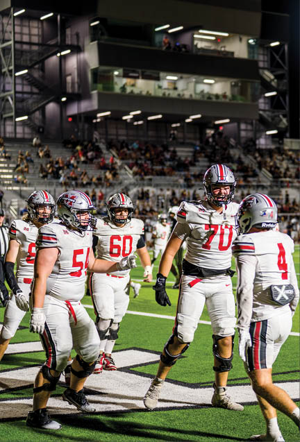 Three football players are standing on the field, one of them is smiling and wearing a black jersey with the number 55. AI generated content