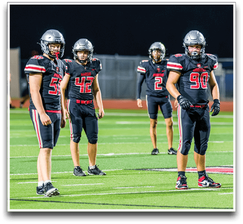 Three football players are standing on the field, one of them is smiling and wearing a black jersey with the number 55. AI generated content