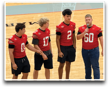 Three football players are standing on the field, one of them is smiling and wearing a black jersey with the number 55. AI generated content