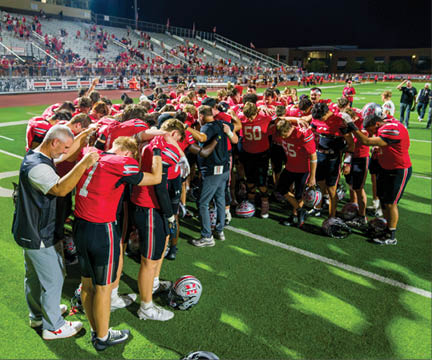 Three football players are standing on the field, one of them is smiling and wearing a black jersey with the number 55. AI generated content