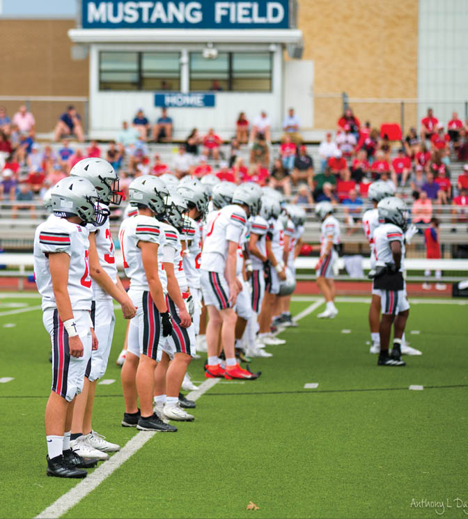 Three football players are standing on the field, one of them is smiling and wearing a black jersey with the number 55. AI generated content