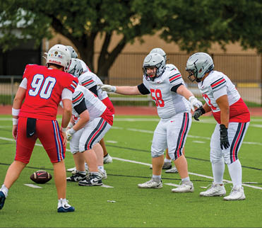Three football players are standing on the field, one of them is smiling and wearing a black jersey with the number 55. AI generated content