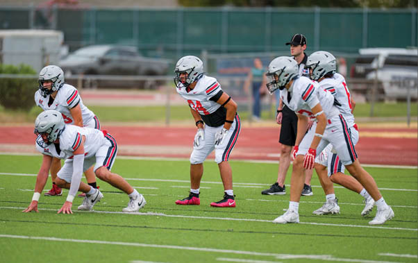 Three football players are standing on the field, one of them is smiling and wearing a black jersey with the number 55. AI generated content
