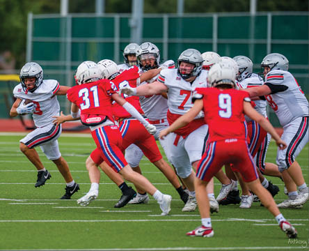 Three football players are standing on the field, one of them is smiling and wearing a black jersey with the number 55. AI generated content