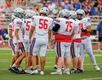 Three football players are standing on the field, one of them is smiling and wearing a black jersey with the number 55. AI generated content