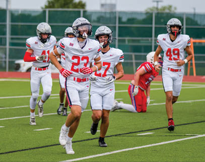 Three football players are standing on the field, one of them is smiling and wearing a black jersey with the number 55. AI generated content