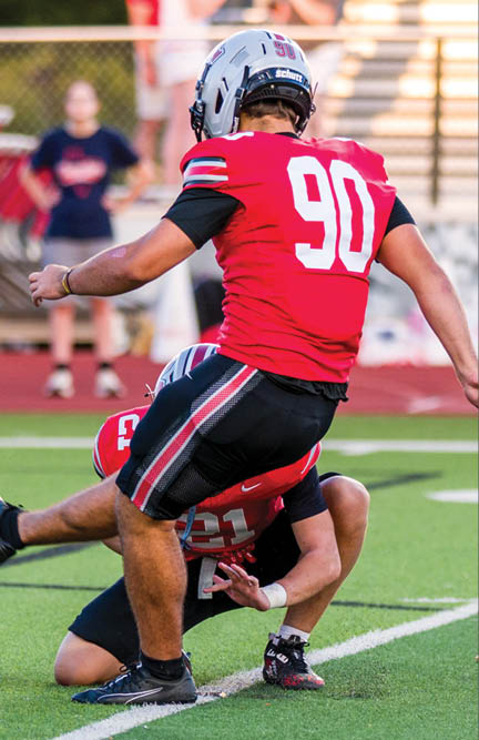 Three football players are standing on the field, one of them is smiling and wearing a black jersey with the number 55. AI generated content