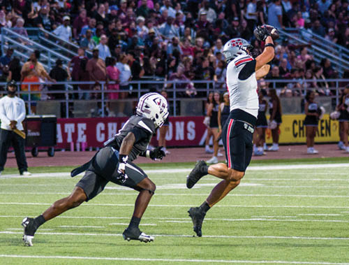 Three football players are standing on the field, one of them is smiling and wearing a black jersey with the number 55. AI generated content