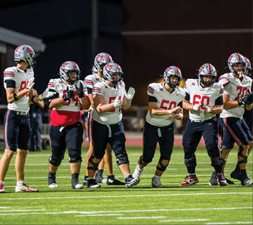 Three football players are standing on the field, one of them is smiling and wearing a black jersey with the number 55. AI generated content