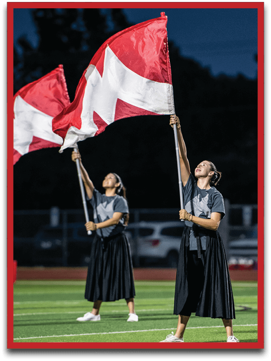 A person is holding a red and white flag against a dark blue sky background. Description generated by AI
