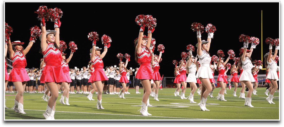 Adults wearing white boots and red skirts are performing a synchronized dance or drill on a green sports field. Description generated by AI