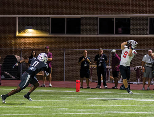 Three football players are standing on the field, one of them is smiling and wearing a black jersey with the number 55. AI generated content