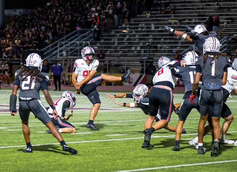 Several people wearing football uniforms are engaged in a close, intense tackle on a grassy field during a game. Description generated by AI