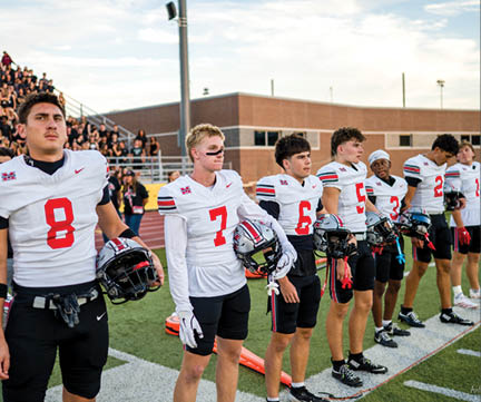 Three football players are standing on the field, one of them is smiling and wearing a black jersey with the number 55. AI generated content