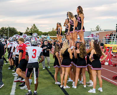 Three football players are standing on the field, one of them is smiling and wearing a black jersey with the number 55. AI generated content