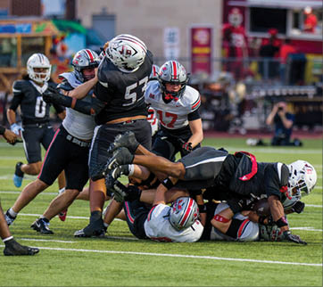 Three football players are standing on the field, one of them is smiling and wearing a black jersey with the number 55. AI generated content