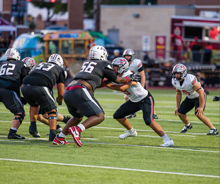 Three football players are standing on the field, one of them is smiling and wearing a black jersey with the number 55. AI generated content