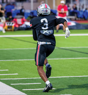 Three football players are standing on the field, one of them is smiling and wearing a black jersey with the number 55. AI generated content