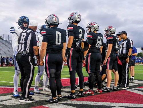 Three football players are standing on the field, one of them is smiling and wearing a black jersey with the number 55. AI generated content