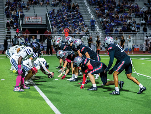 Three football players are standing on the field, one of them is smiling and wearing a black jersey with the number 55. AI generated content