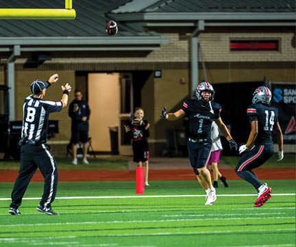 Three football players are standing on the field, one of them is smiling and wearing a black jersey with the number 55. AI generated content