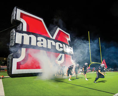 Three football players are standing on the field, one of them is smiling and wearing a black jersey with the number 55. AI generated content