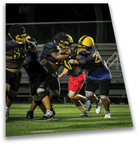 A group of football players in a field, one player is tackling another player. AI generated content