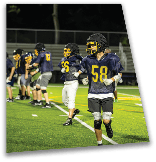 A group of young men are playing football on a field. One of the players is wearing a knee brace. AI generated content