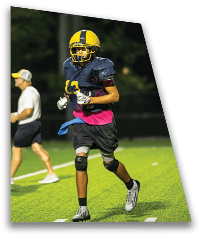 A group of football players on a field. One player is wearing a pink shirt. AI generated content