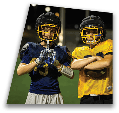Two football players pose on the field, one wearing a blue jersey and the other in yellow. AI generated content