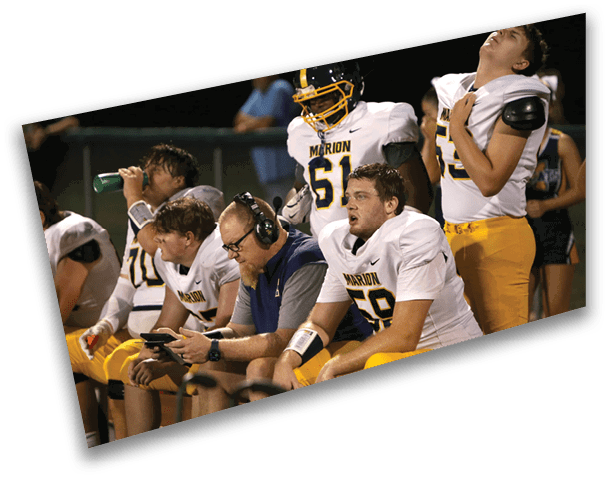 A group of football players sitting on a bench, some with their hands on their heads. AI generated content