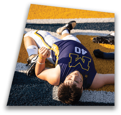 A football player is lying on the ground with his arm extended. AI generated content