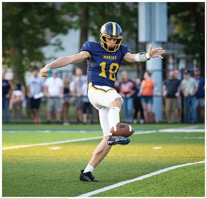 A man in a blue and yellow football uniform is kicking a football on a field. AI generated content