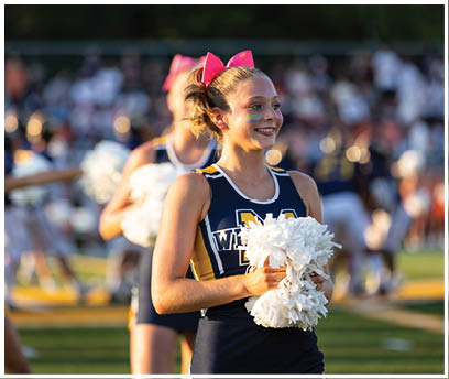 A cheerleader in a blue and yellow uniform holds a white pom pom. AI generated content