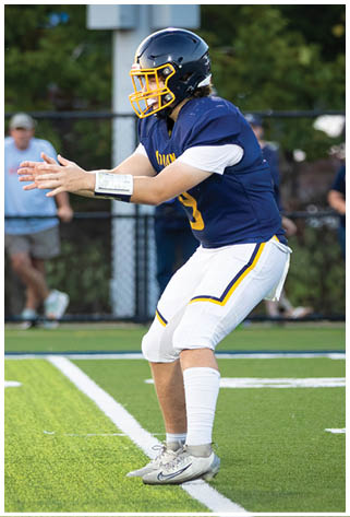 A man in a blue jersey is throwing a football on a field. AI generated content