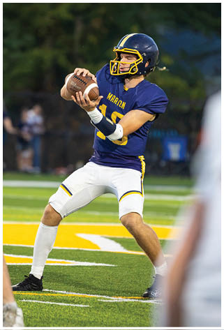 A football player in a blue uniform is throwing a football on the field. AI generated content