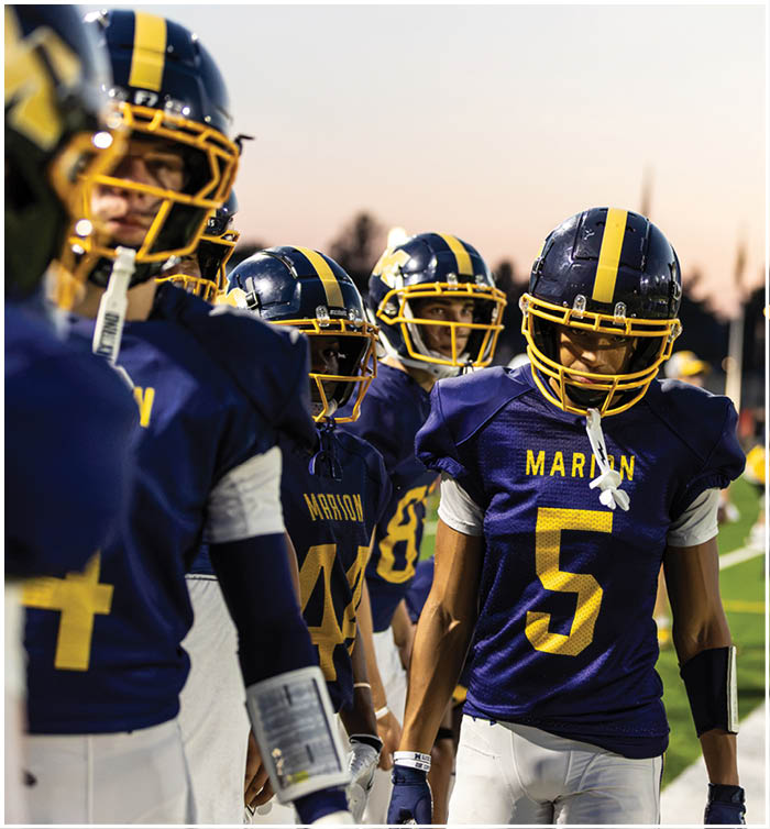 A group of football players wearing blue and yellow uniforms are standing on the field. AI generated content