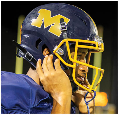 A football player wearing a blue jersey with the number 14 on it is talking on his cell phone. AI generated content