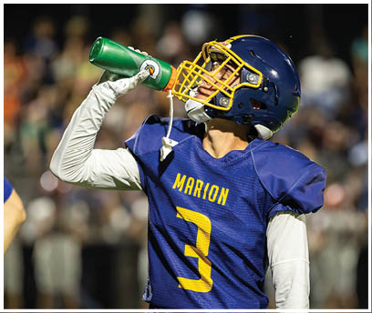 A football player drinking water from a green bottle. AI generated content