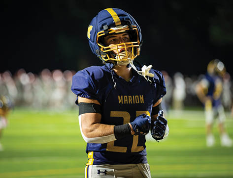 A football player wearing a blue helmet and jersey stands on the field. AI generated content