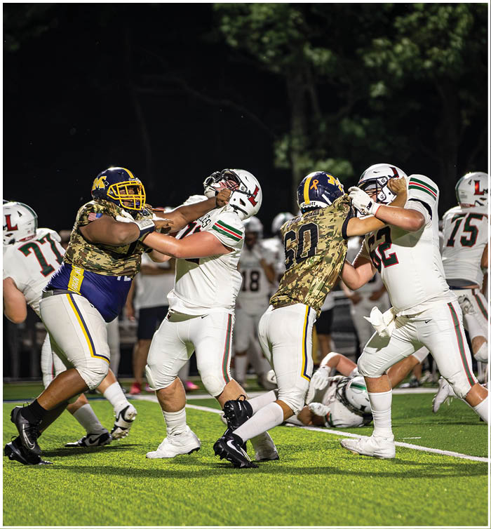 A group of football players on a field, some of them wearing camouflage uniforms. AI generated content