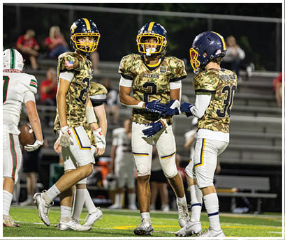 A group of football players wearing camouflage uniforms are standing on the field. AI generated content