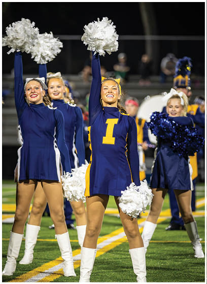 A group of cheerleaders in uniforms are performing on a field. AI generated content