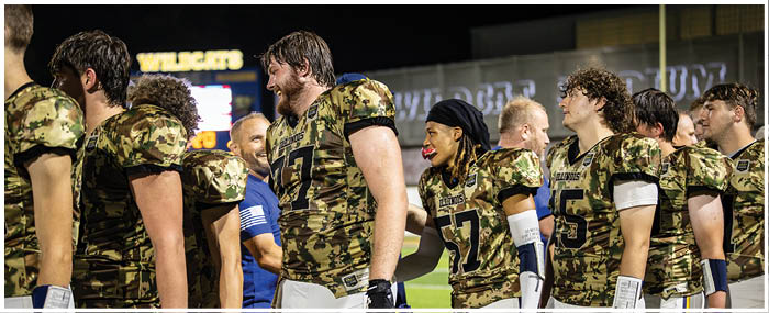 A group of football players wearing camouflage uniforms and helmets. AI generated content