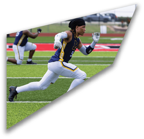 A person in athletic clothing is lunging forward on a football field while another person kneels in the background. Description generated by AI