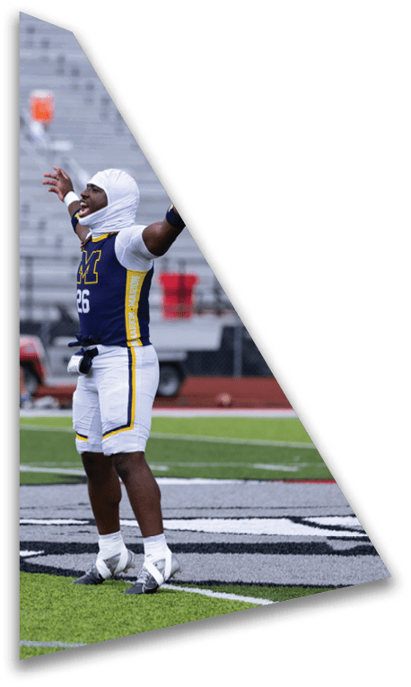 A person in a football uniform with the number 26 is standing on a field with arms raised, wearing a white head covering and cleats. Description generated by AI