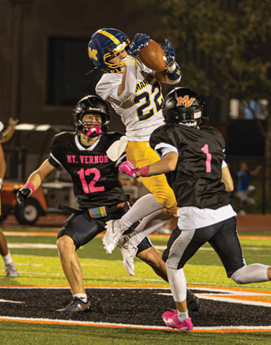 People in sports uniforms are actively playing football on a field under stadium lights. Description generated by AI