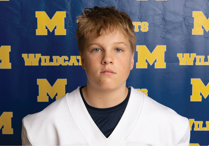A person with short, tousled hair and blue eyes is partially visible in front of a blue background with yellow text. Description generated by AI