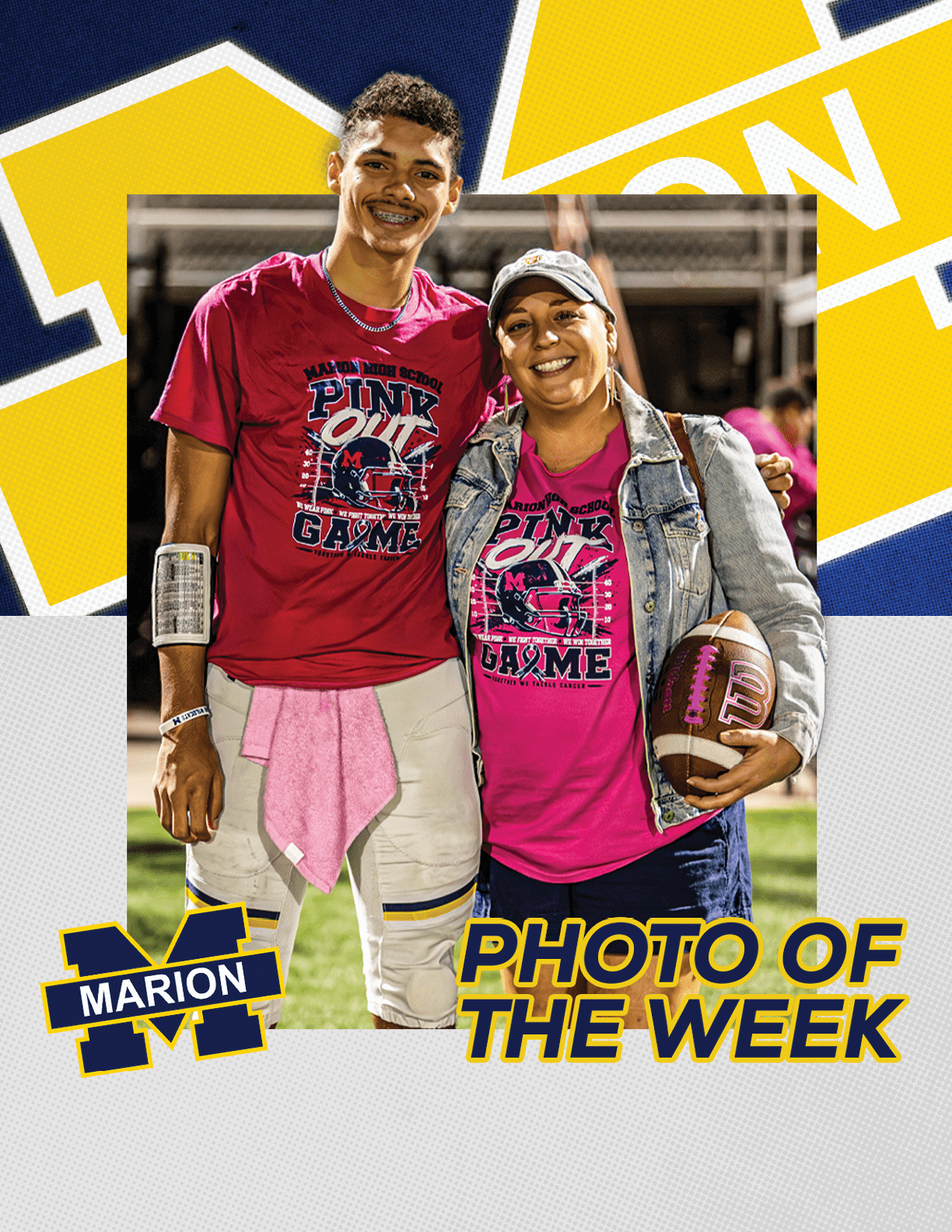 Two people wearing matching pink shirts stand together on a sports field with one holding a football and both smiling. Description generated by AI